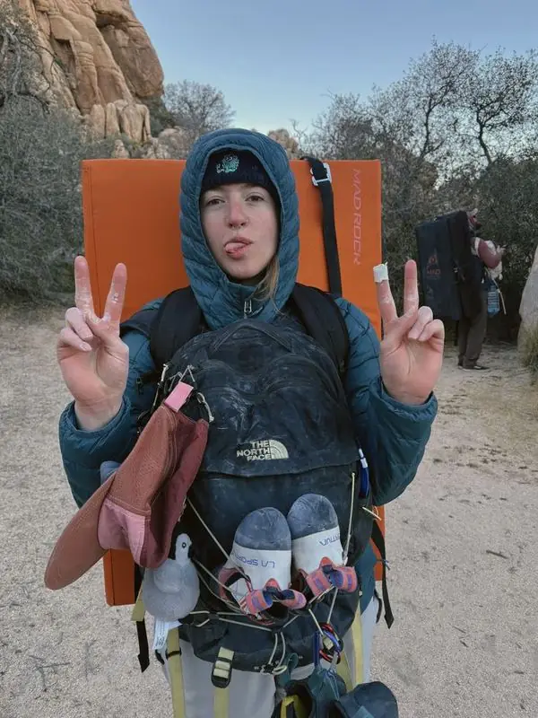 Climber with crash pad giving peace signs