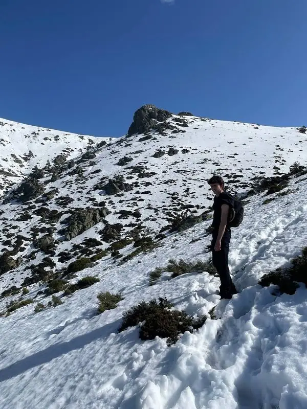 Hiker on a steep snowy slope below a rocky peak